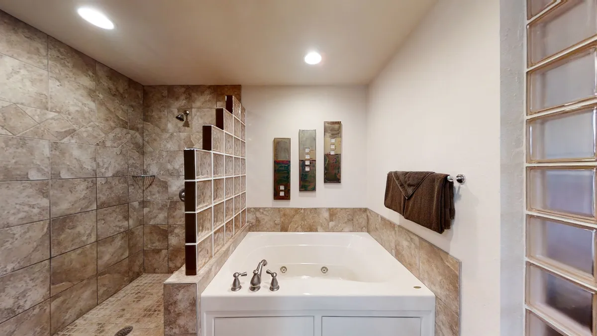 A spa-inspired bathroom with a luxurious jacuzzi tub, a separate walk-in shower area, and tasteful wall art. The serene setting invites relaxation and indulgence, perfect for rejuvenating after adventurous days.