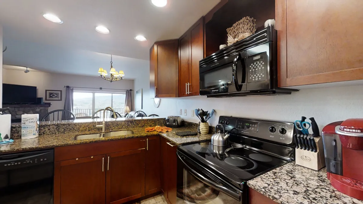 A fully equipped kitchen is highlighted here, with a granite countertop, black appliances, a kitchen island, and a window offering a glimpse of the outdoors. The space is both functional and inviting, ideal for preparing meals and gathering with family or friends.