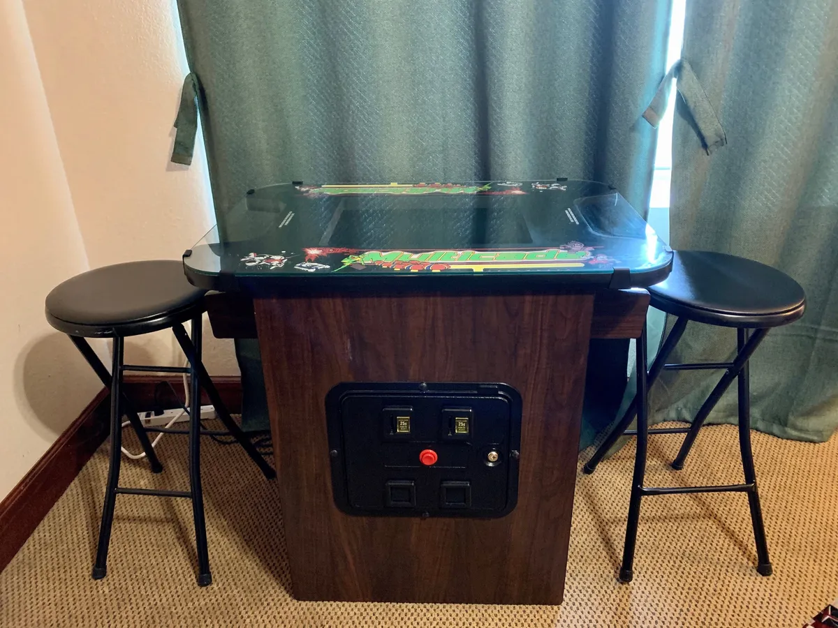 A light-filled room with an arcade game table and bar stools, inviting guests to enjoy playful moments together. The setup suggests fun and entertainment, making it ideal for kids or friends to unwind.